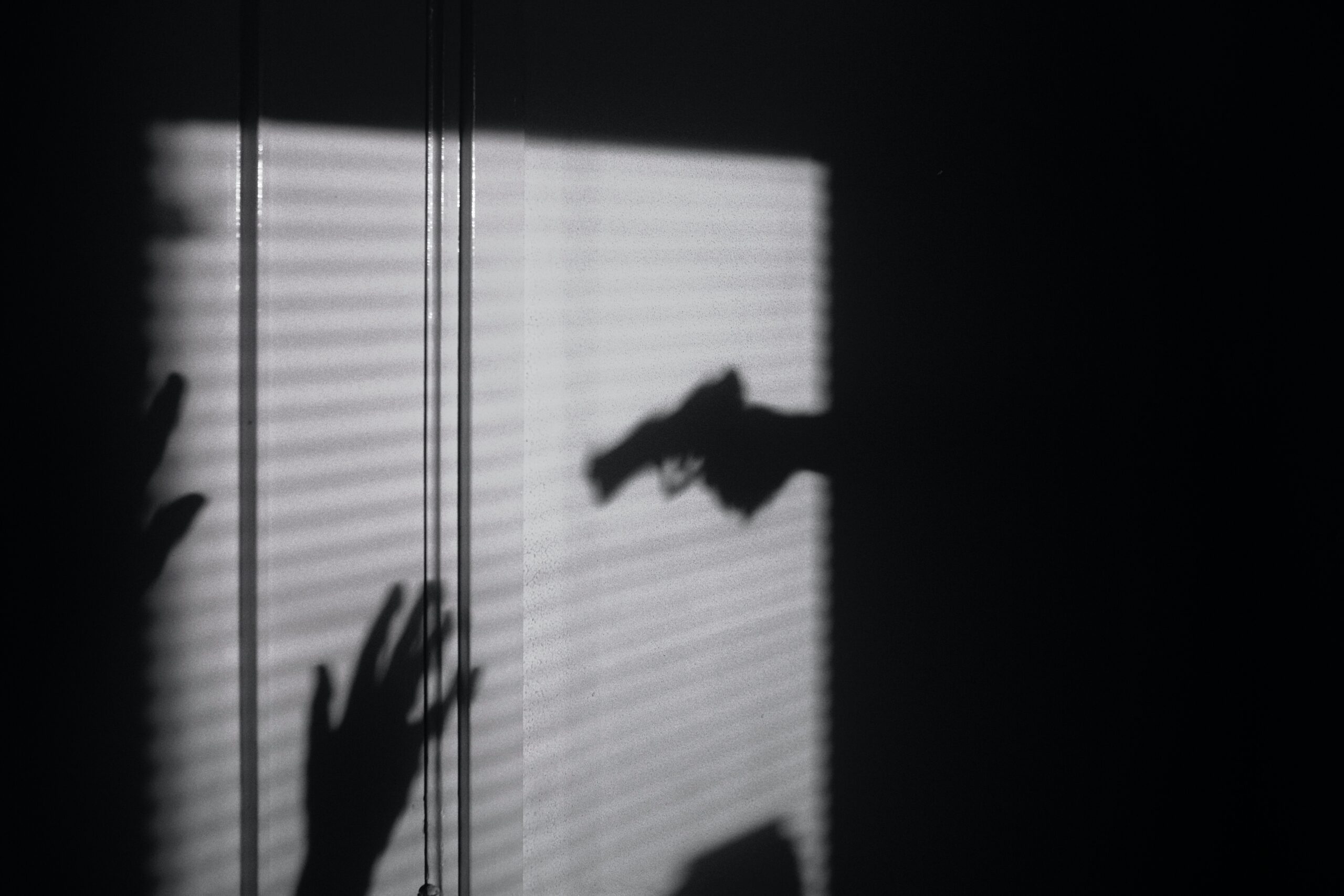 shadowed silhouette of someone held at gunpoint